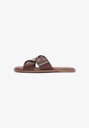 Sandale en cuir marron avec design à sangles croisées, semelle plate et accents dorés subtils pour une touche supplémentaire. Texture lisse partout.