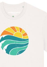 Witte katoenen T-shirt met een circulaire afbeelding van een oranje zon en turkooise golven, met een textuurlagen finish.