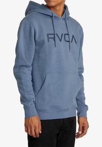Felpa blu chiaro realizzata in tessuto morbido, con tasca a marsupio frontale, cappuccio con cordoncino e un audace logo "RVCA" nero sul petto.