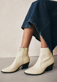 Krämfärgade läderankelbooties med spetsig tå och sidodragkedja. Har en staplad klack och subtila sömdetaljer.