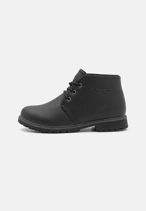 Bottines noires en cuir texturé. Présentent un bout arrondi, un design minimaliste et un laçage à l'avant avec œillets. Semelle en caoutchouc avec un léger profil.