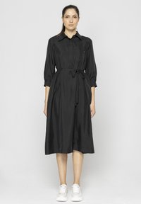 Czarna sukienka koszulowa z kołnierzykiem, rękawami o d�ługości trzech czwartych, przewiązywana w talii i z bocznymi kieszeniami. Gładki, miękki materiał o luźnym kroju.