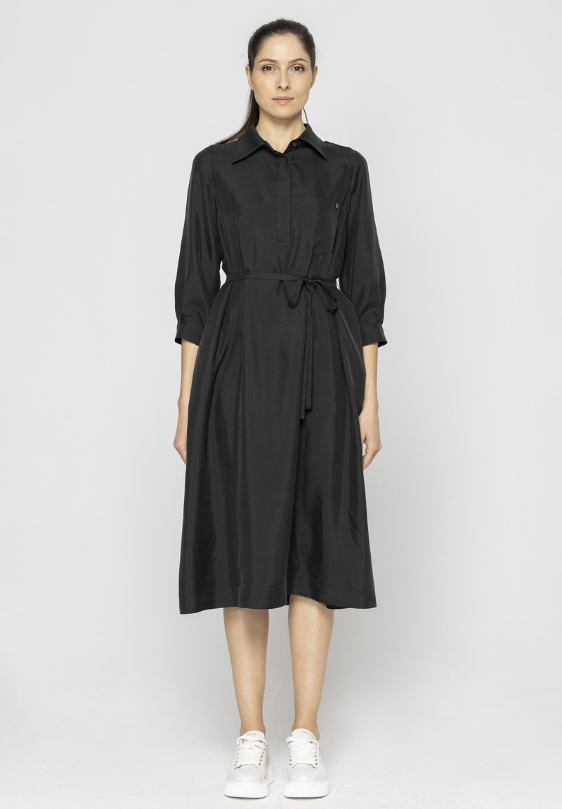Czarna sukienka koszulowa z kołnierzykiem, rękawami o długości trzech czwartych, przewiązywana w talii i z bocznymi kieszeniami. Gładki, miękki materiał o luźnym kroju.