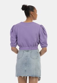 Lavendel cropped sweatshirt med puffærmer og elastisk talje, parret med en lyseblå denim mini nederdel med rå kant og baglommer.