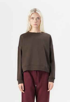 Brown cropped sweatshirt with dropped shoulders, wide cuffs, and a neutral texture, paired with burgundy drawstring pants.
