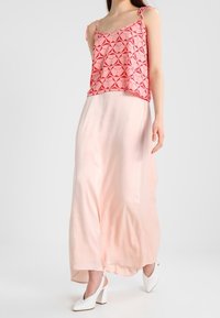 Rosa mönstrad ärmlös topp med en genomskinlig persikofärgad maxikjol. Outfiten har delikata axelband och mjuka, flödande material.