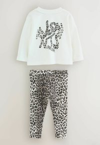 Conjunto de camiseta blanca de manga corta con diseño de estampado de leopardo negro y leggings de estampado de leopardo negro con cintura elástica.