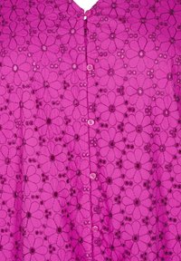Růžová květinová košile na knoflíky s výstřihem do V, která má krajkovou strukturu a kulaté růžové knoflíky, zdobená vzorovanými květinovými motivy.