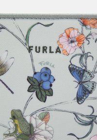 Tkanina w kwiatowe wzory z niebieskimi jagodami i zieloną żabą. Ma jasnoniebieskie tło oraz nazwę marki "Furla" w ciemnozielonym kolorze.