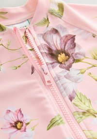 Tissu de maillot de bain à motif floral rose avec une fermeture éclair à l'avant. Le design comprend de grandes fleurs violettes et blanches avec des feuilles vertes.