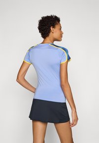 Camiseta deportiva de manga corta en azul claro con acentos en amarillo y azul oscuro, fabricada con un material que absorbe la humedad, y con un diseño ajustado.