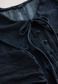 Mørkeblå denimkjole med krave, bindelukning og knapdetaljer. Tekstureret stof med en glat finish og let glans.
