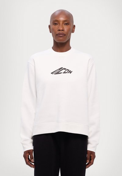 Sweat-shirt blanc en coton, avec un col rond et une coupe cropped. Graphique de logo noir sur la poitrine. Manches longues avec des poignets côtelés.
