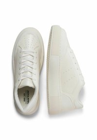White sneakers with a smooth leather upper, rounded toe, lace-up front, perforated detailing, and a textured rubber sole.