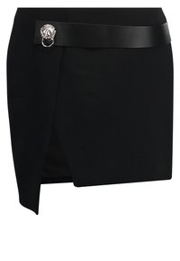 Mini-jupe asymétrique noire avec une large ceinture en cuir ornée d'une boucle tête de lion argentée et d'un détail anneau à la taille.