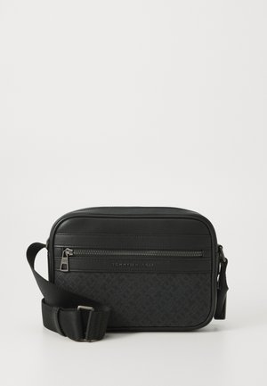 Juodas krepšys per petį su lygiu odiniu viršumi, užtraukiama kišenė, ir tekstūruota audinio priekinė dalis su subtiliu raštu. Pridedamas reguliuojamas diržas.