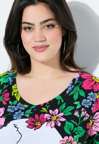 Short-sleeve, black floral T-shirt featuring vibrant pink, blue, and green flowers. V-neck design with a smooth fabric texture.