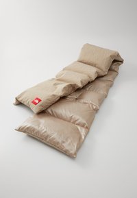 Beige padded sleeping mat with textured and smooth sections. Features a red logo tag and folds for portability. Soft, lightweight material.