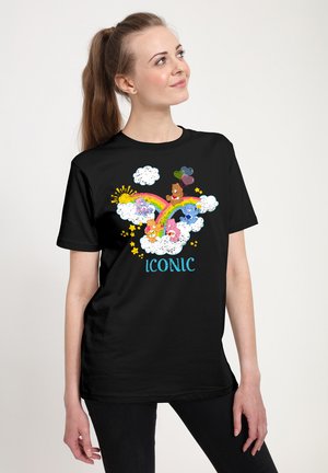 Sort t-shirt med farverigt grafisk design af dyr, en regnbue, skyer og sol, med ordet "ICONIC" i blå tekst.