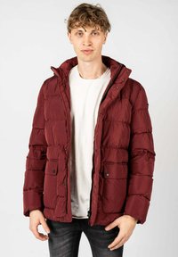 Giacca imbottita bordeaux con colletto alto, chiusura con zip e tasche con bottone a pressione. Realizzata in materiale sintetico lucido con pannelli trapuntati.