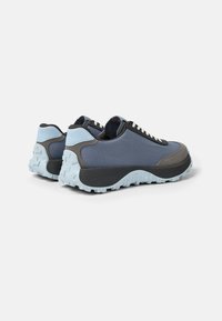 Zapatillas deportivas bajas para hombre con parte superior de tela azul oscura, suela de goma azul clara y acentos en gris contrastantes. Detalles texturizados en toda la superficie.