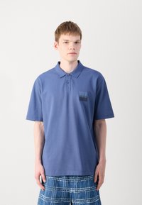 Blå pikétröja av bomull med krage, korta ärmar och en bröstficka med HUGO-logotyp i kontrasterande färg.