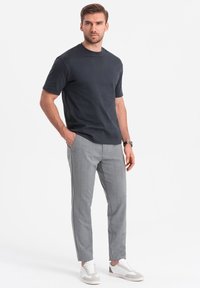 T-shirt corto grigio scuro a maniche corte abbinato a pantaloni a quadri grigio chiaro e sneakers bianche. Design semplice con una vestibilità comoda.