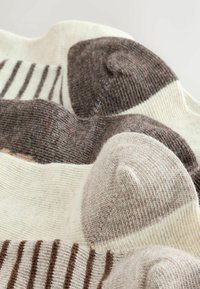 Close-up of soft wool socks in beige and brown with striped patterns, displayed overlapping on a light background.