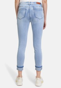 Ljusblå denimjeans med en figursydd design, som har hög midja, uppvikta benfållar och två bakfickor. Läderlappar vid midjan.