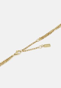 Bracciale in catena d'oro con anelli intrecciati, dotato di chiusura a moschettone e di un tassello piatto inciso con "BOSS." Texture liscia, finitura lucida.