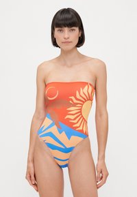 Halterlös baddräkt i orange, blå och beige. Har sol- och bergsgrafik, med högskuren benöppning och mjuk tygtextur.