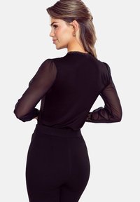 Czarna bluzka z długimi przezroczystymi rękawami, teksturowanym korpusem, okrągłym dekoltem i dopasowanym krojem. Widok z tyłu pokazuje gładki, elegancki design.