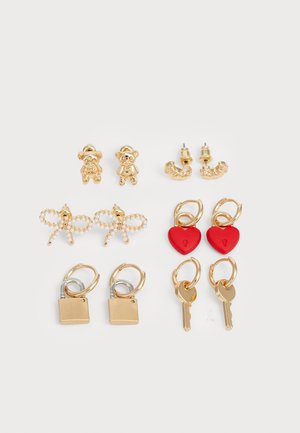 Gold-tone earring set features bear, butterfly, heart, lock, and key designs. Includes pearl accents, red hearts, and mixed metal elements.