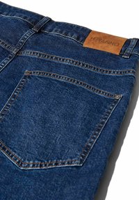 Dunkelblaue Denim-Jeans mit glatter Textur, kontrastierenden Nähten und einem braunen Lederetikett mit dem "HEYANNO"-Wappen am Bund.