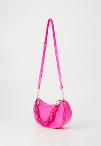 Borsa in suede rosa con forma curva, caratterizzata da una maniglia decorata con perline e una tracolla regolabile. Texture liscia e dettagli in hardware argentato.