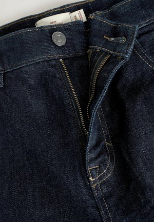 Dunkelblaue Denim-Jeans mit einem Reißverschluss, Metallknopfverschluss und kontrastierenden gelben Nähten. Verfügt über ein klassisches Fünf-Taschen-Design.