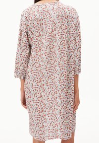 Robe fleurie avec un motif pastel de petites fleurs blanches, rouges et bleues sur un fond clair. Manches trois-quarts, coupe ample.