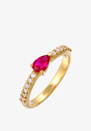Zlatý prsteň s hruškovým červeným kameňom v strede, zdobený malými čírymi kameňmi pozdĺž obrúčky pre detaily a textúru.