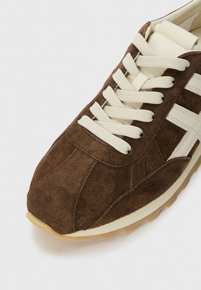 Braune Wildleder-Sneaker mit cremefarbenen Schnürsenkeln und Akzenten. Verfügt über ein strukturiertes Obermaterial und eine Gummisohle, die ein klassisches sportliches Design zeigt.