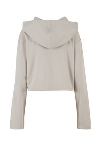 Haut beige cropped avec une grande capuche, des manches longues et une texture lisse. Présente un design simple et uni sans motifs ni accents.