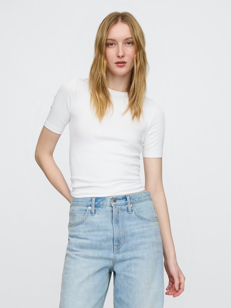 Bijela majica kratkih rukava od glatkog pamuka, uparena s visokim svijetloplavim trapericama s klasičnim dizajnom s pet džepova.