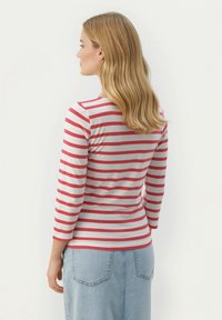 Punase ja valge triibuline pikako sleeves topp, mis on varustatud ümarat kaelusest ja vormitud disainiga. Sobib kõrge vöökohtaga teksaseeliku juurde.