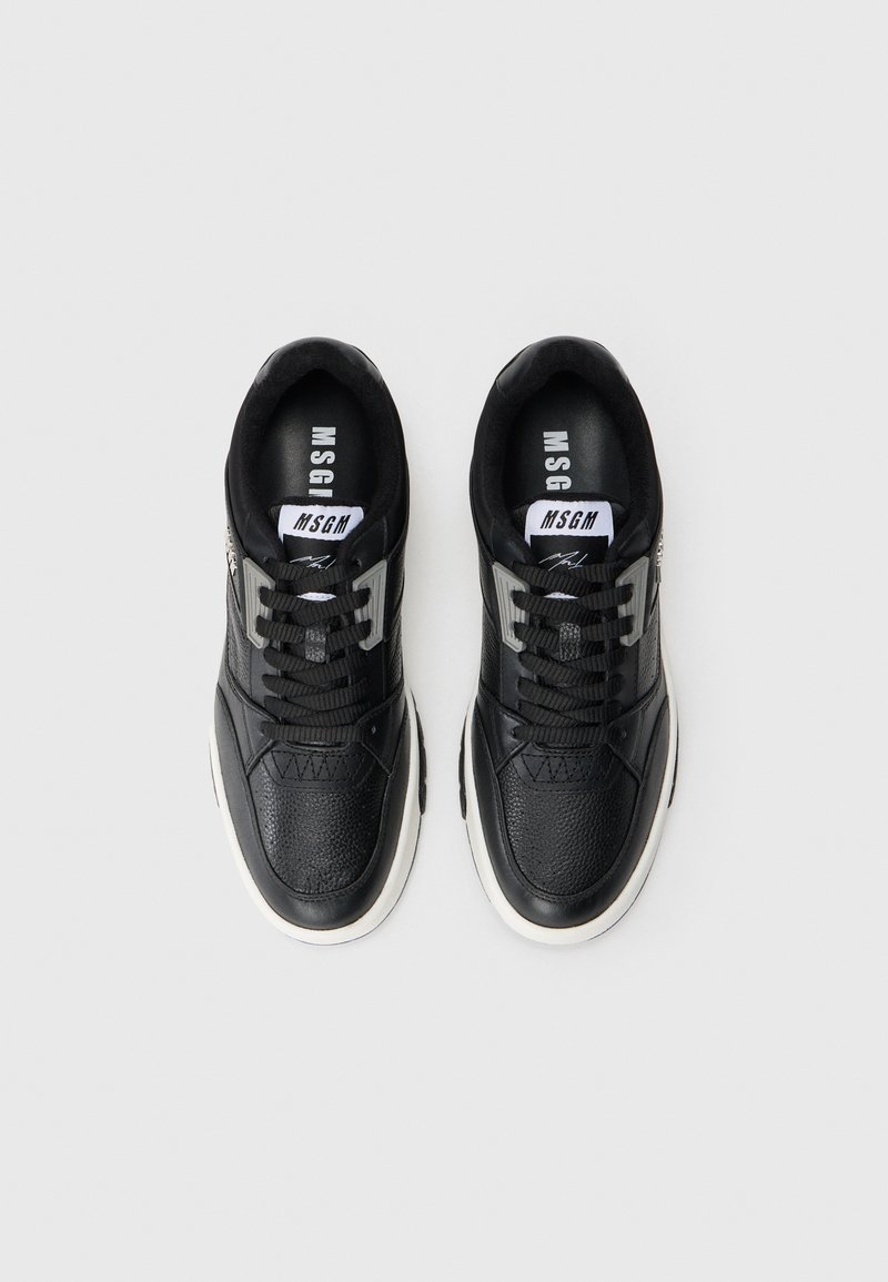 Schwarze Sneaker mit einem strukturierten Obermaterial aus Leder, Mesh-Details, gepolstertem Kragen und einer kontrastierenden weißen Sohle. Markenlogo auf der Zunge.