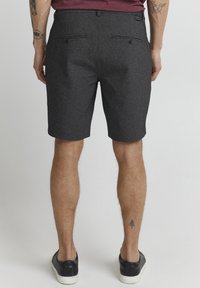Gray woven shorts with a straight cut, mid-length, two back pockets, and a textured fabric. Worn with black sneakers.