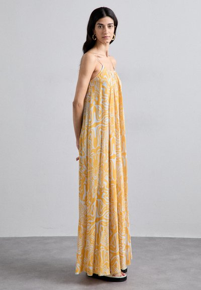 Vestido maxi en amarillo con patrones abstractos blancos, hecho de material ligero. Presenta tirantes finos y una silueta fluida.