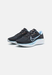 Baskets de sport noires avec une tige en mesh respirant, accents bleu clair, détails orange, semelle blanche rembourrée et logo contrastant.