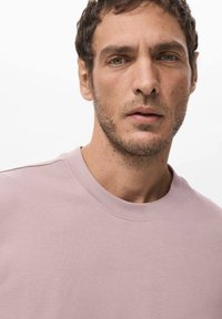 Light pink, crew-neck t-shirt made of soft fabric. Features a classic fit with short sleeves and subtle seam details.