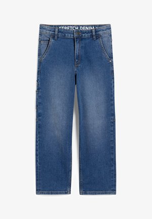 Bambino con felpa verde Hunter x Hunter con stampa del personaggio, jeans blu, scarpe bianche, in piedi davanti a uno sfondo chiaro e semplice.