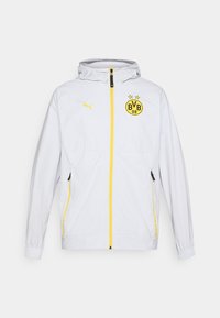 Veste blanche du Borussia Dortmund avec zip jaune, logo Puma sur la poitrine gauche et écusson du club BVB 09 sur la poitrine droite avec capuche.