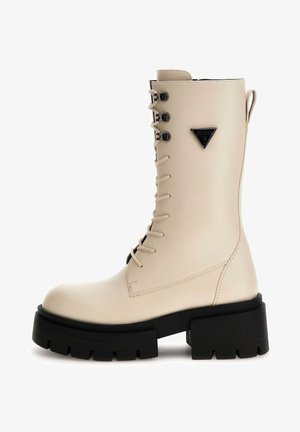 Stivaletti in ecopelle beige con lacci e suola platform nera chunky, accentuati da dettagli metallici e un logo triangolare sul lato.